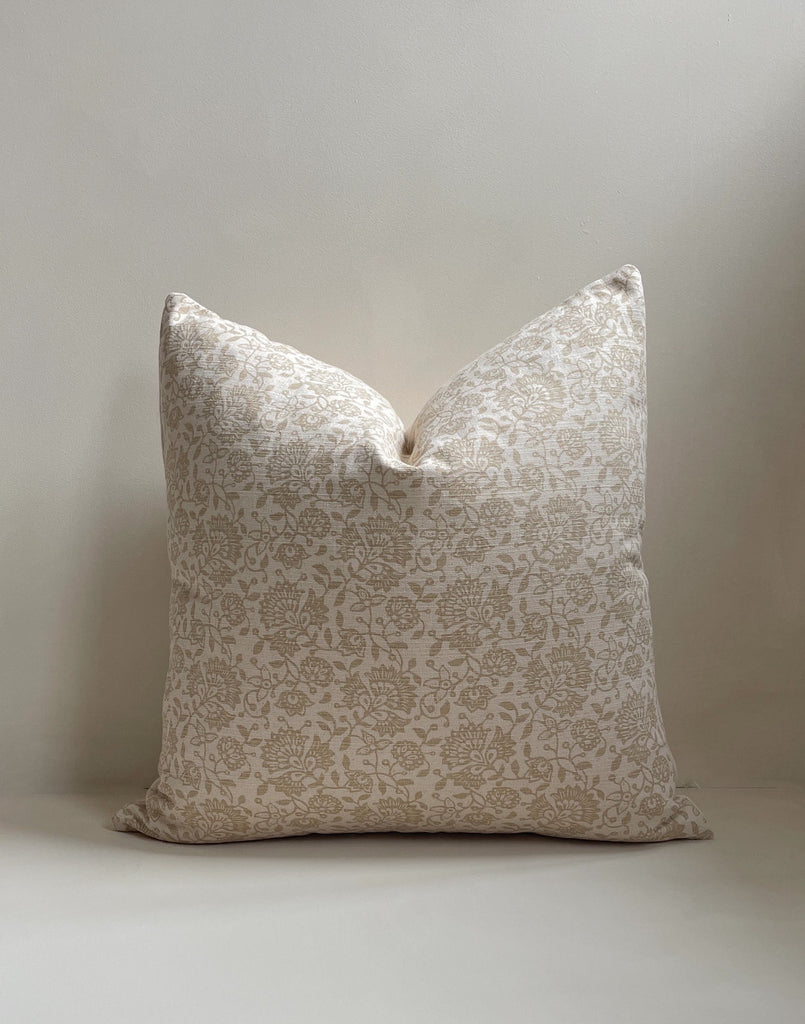 Front view of a 20x20” square luxury cotton hand-woven cushion cover in a neutral tone featuring a tan floral pattern. It has a textured cotton back and invisible zipper. Displayed against a neutral limewash background, made in the United Kingdom